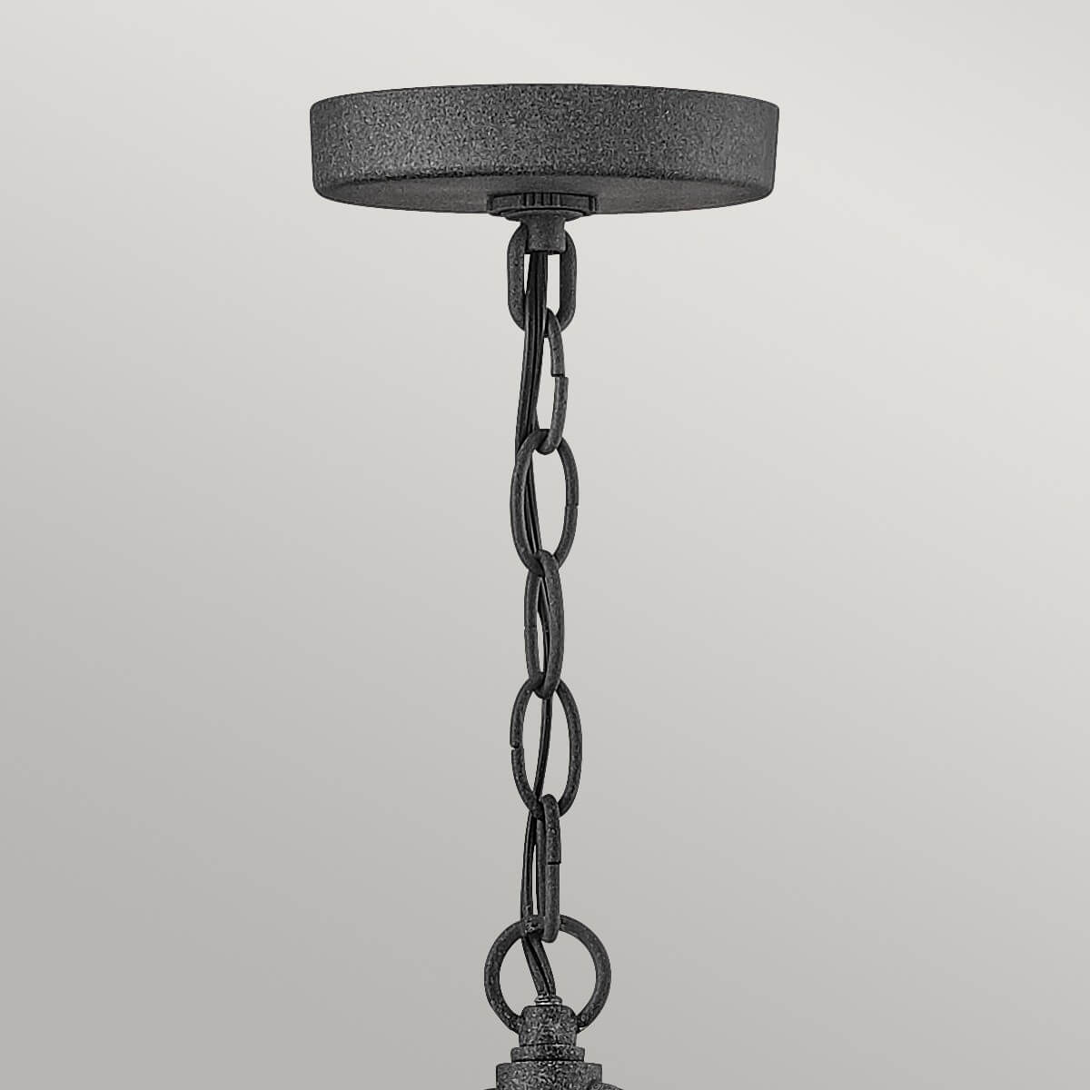 Détail du support plafond et de la chaîne métallique texturée de la suspension.