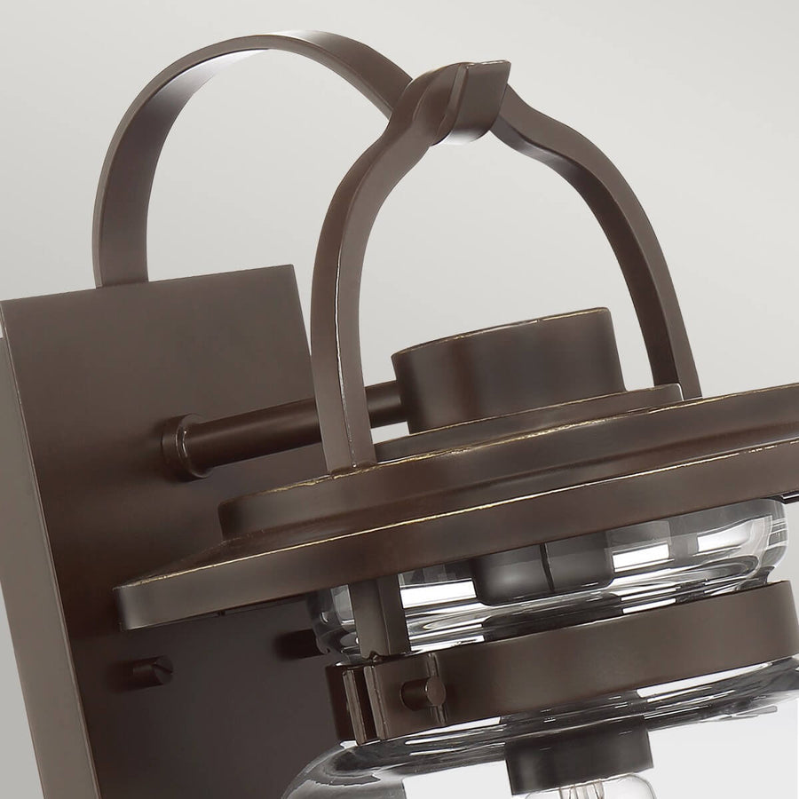 Gros plan sur l'arche supérieure et la platine murale en métal bronze.