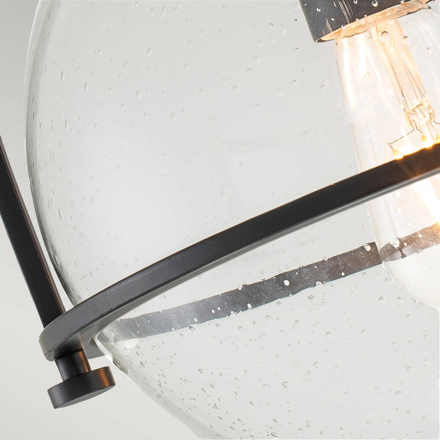 Vue rapprochée de l'arceau noir enserrant le verre bullé, ampoule allumée