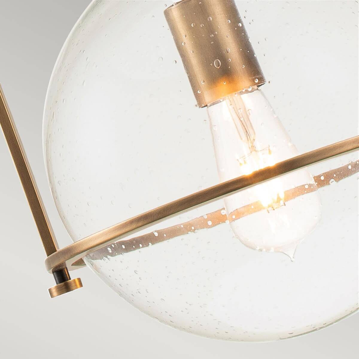 Gros plan sur la douille, l'ampoule et la sphère en verre bullé traversée par une barre