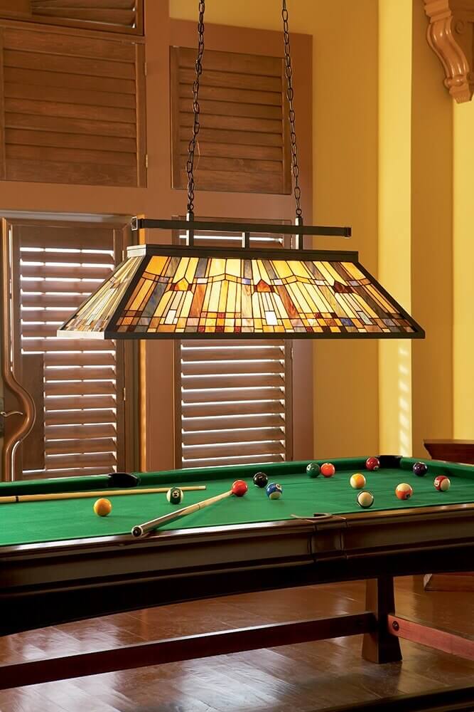 Suspension au-dessus d'une table de billard en bois, éclairant le tapis vert et les boules.