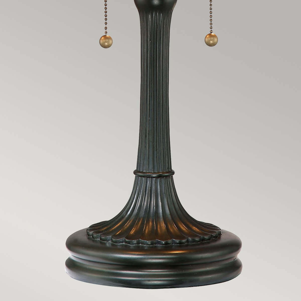 Détail du pied bronze cannelé et de sa base moulurée posée sur fond clair