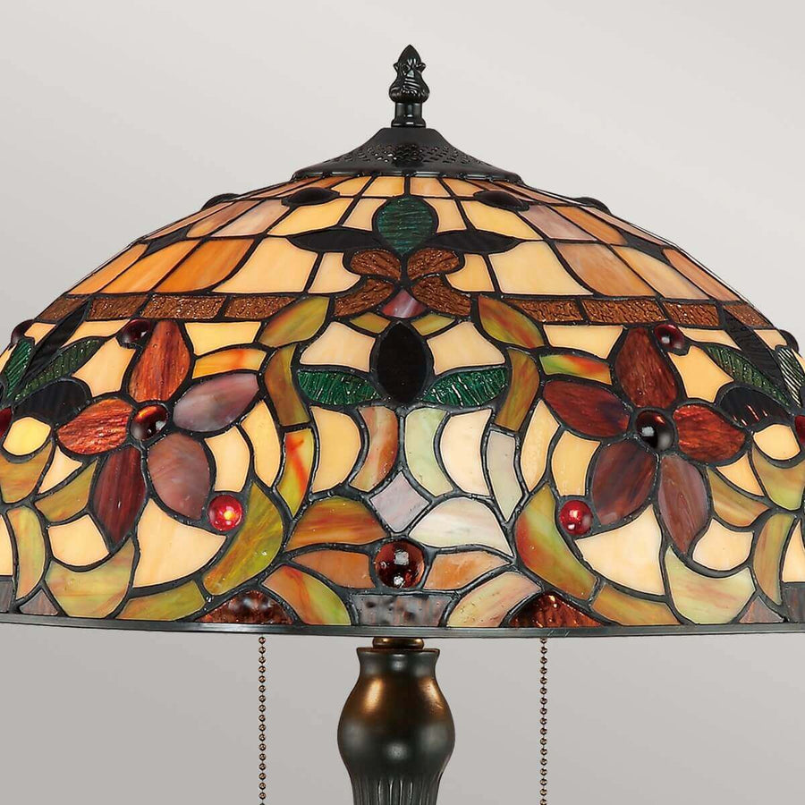 Vue rapprochée du sommet de l'abat-jour, fleuron métallique et motifs floraux en verre