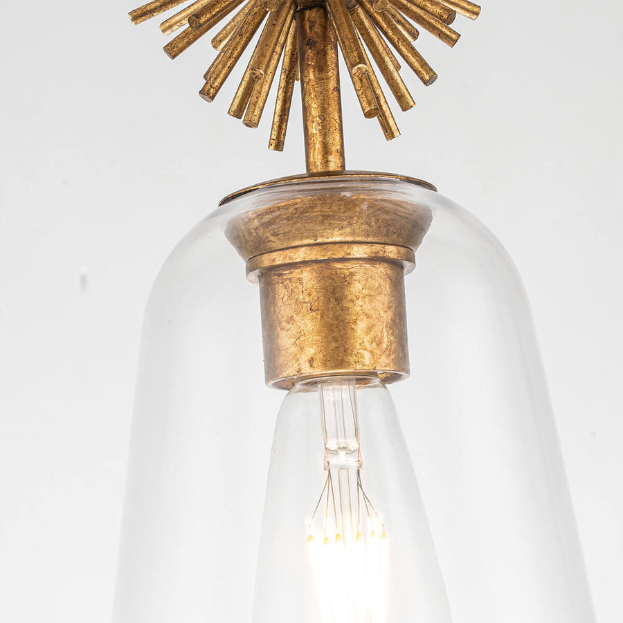 Détail de la douille dorée et du haut de l'abat-jour en verre transparent avec ampoule.