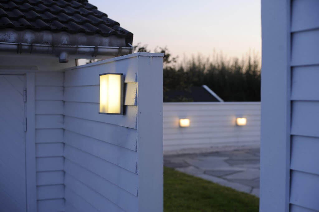 Luminaire installé sur un mur extérieur au crépuscule, autres appliques en arrière-plan