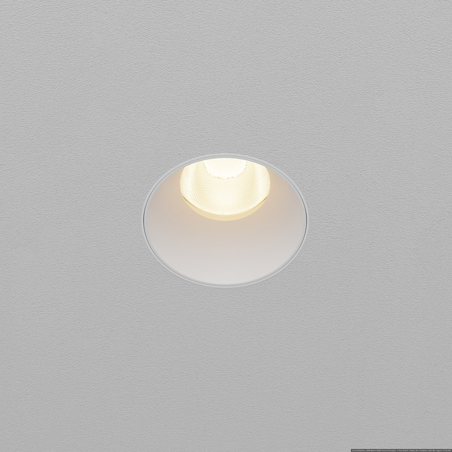 Spot encastré rond blanc allumé, vu de dessous dans un plafond gris texturé