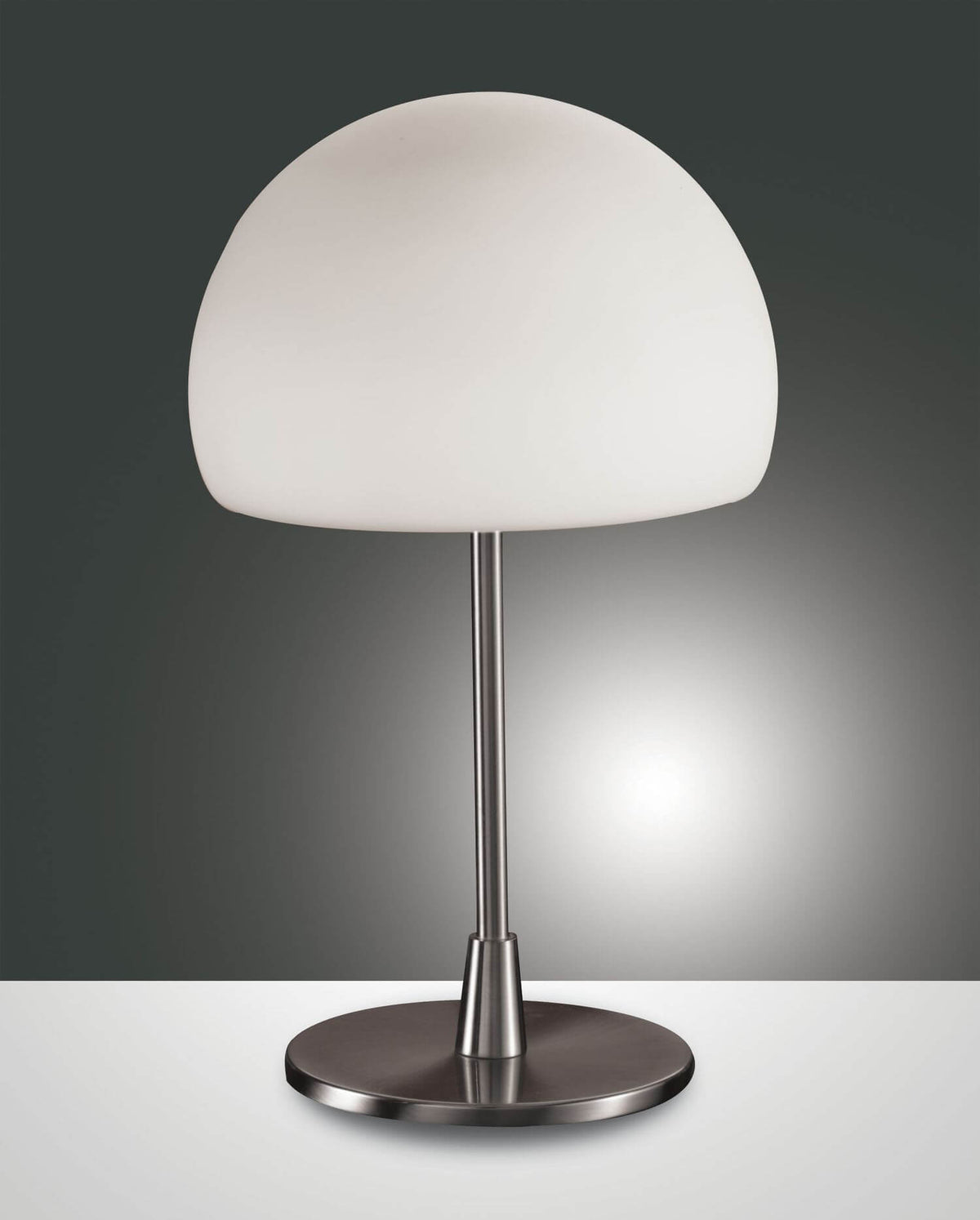Lampe à poser de face avec abat-jour blanc et pied chromé sur fond gris.
