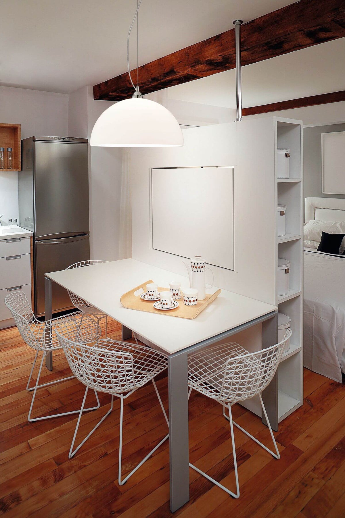 Suspension blanche suspendue au-dessus d'une table à manger, dans un intérieur contemporain avec chaises filaires.