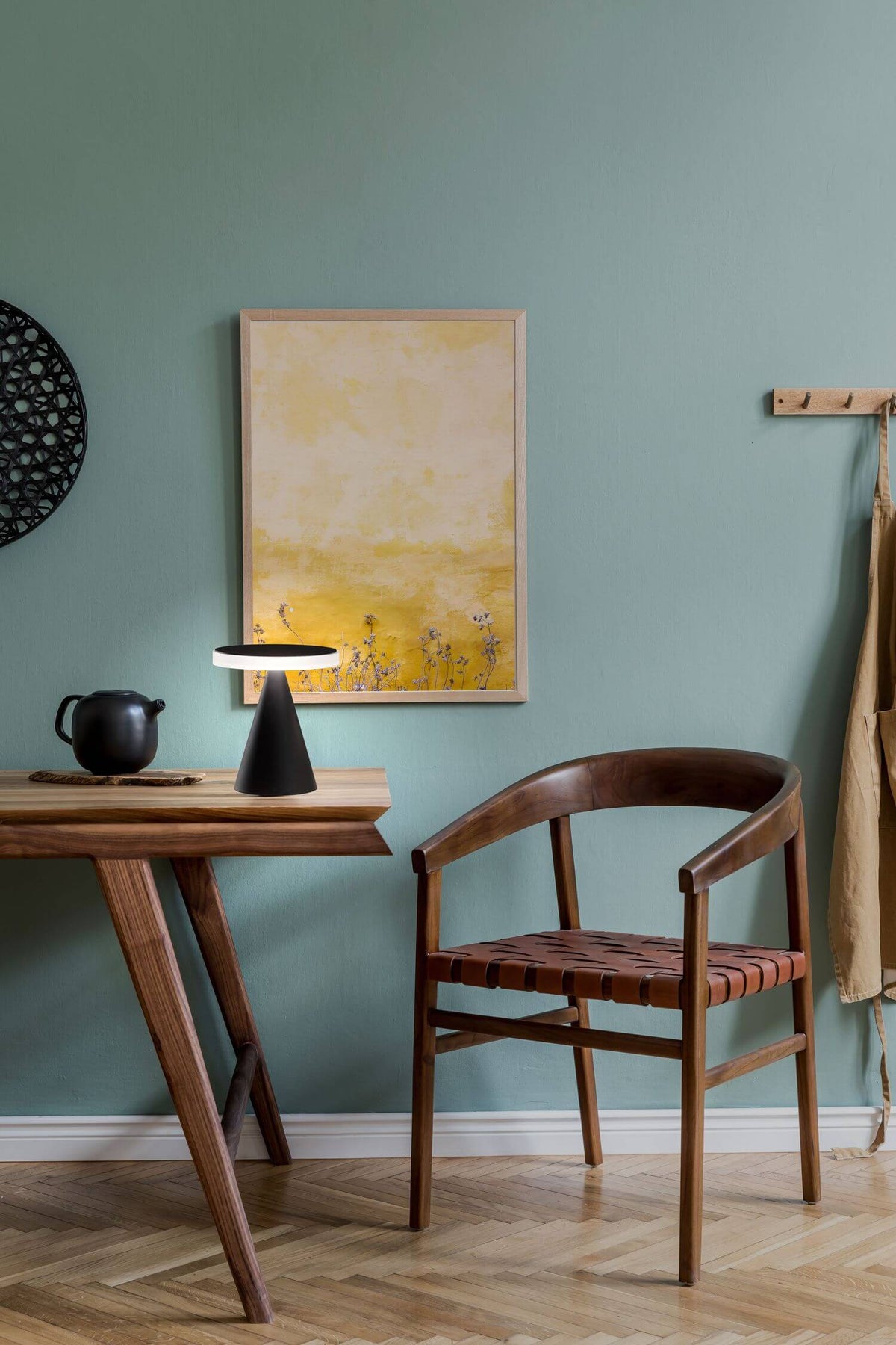 Mise en ambiance sur un bureau en bois, mur vert et chaise en cuir.