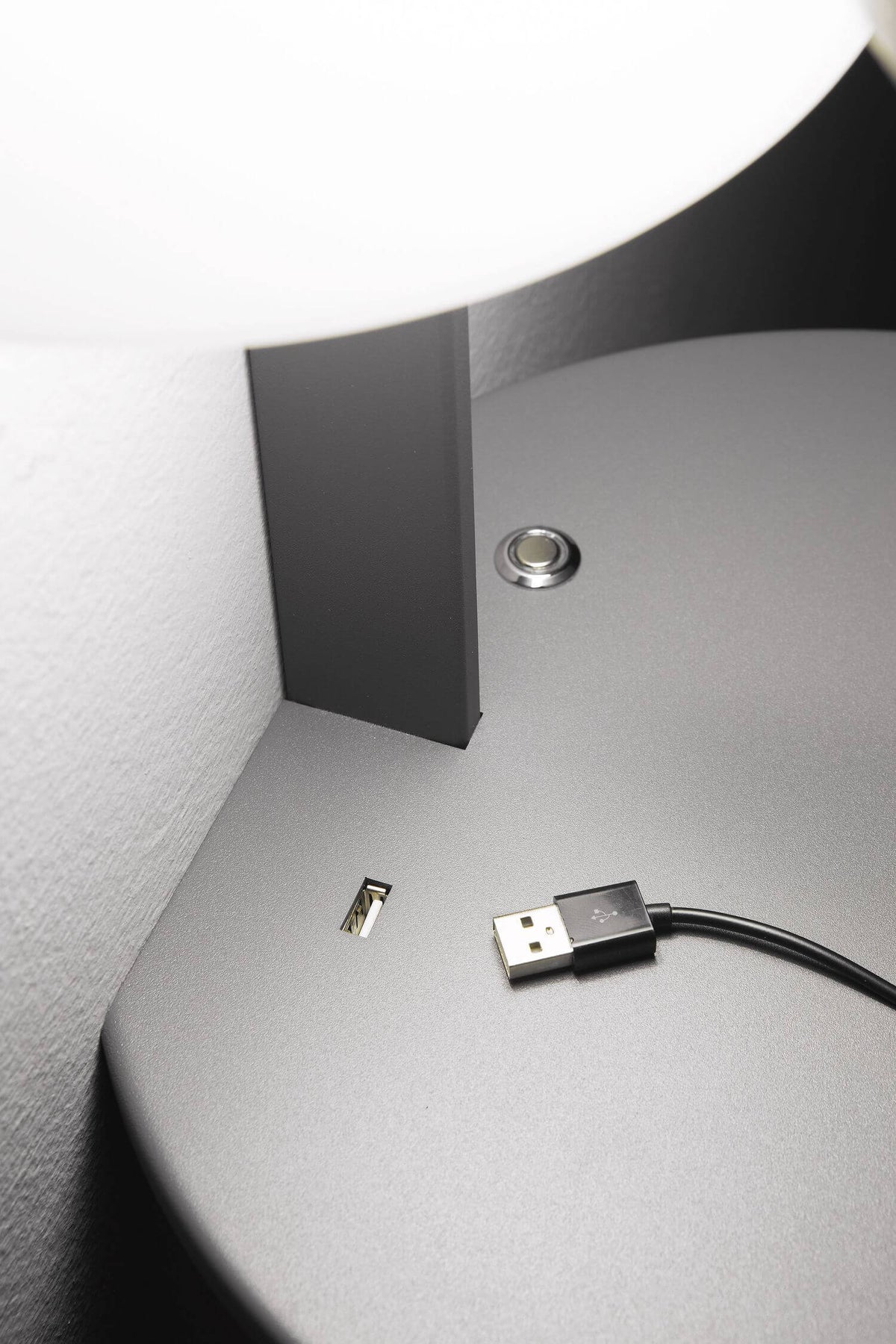 Détail de la tablette ronde montrant le port USB et le bouton tactile
