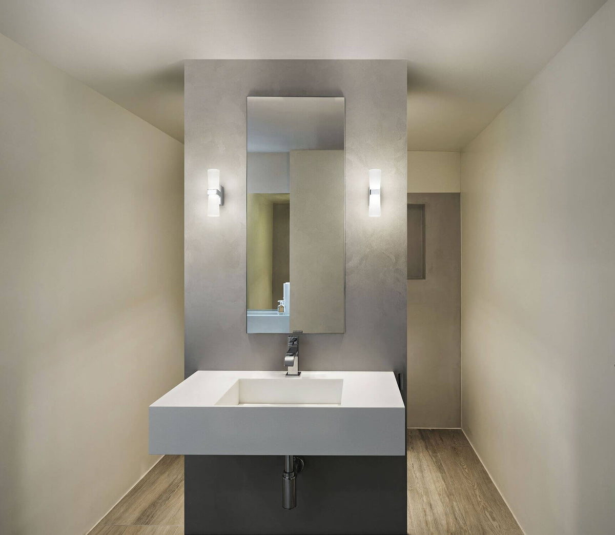 Mise en ambiance salle de bain avec deux appliques murales chromées autour du miroir.