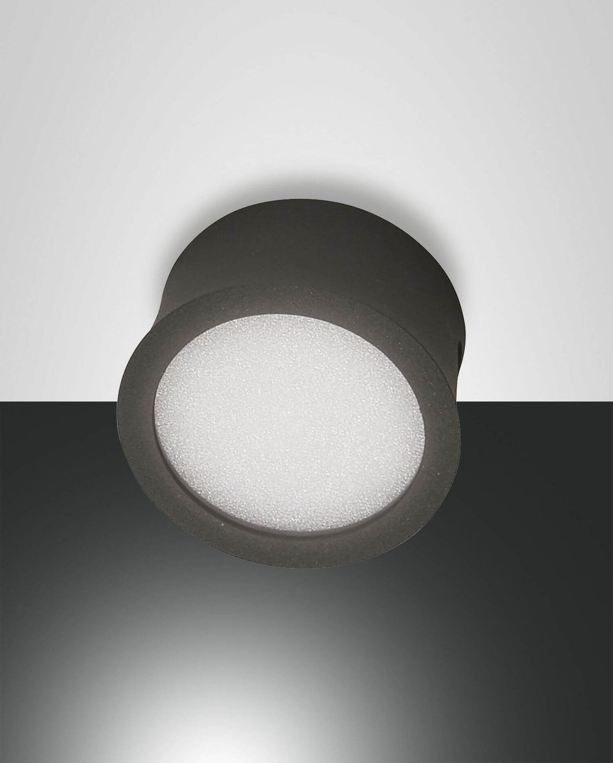 Vue de dessous du spot cylindrique anthracite, diffuseur blanc granuleux allumé dans l'obscurité