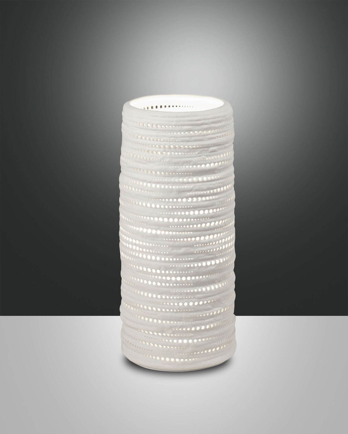 Lampe à poser cylindrique blanche perforée de face sur fond gris sombre