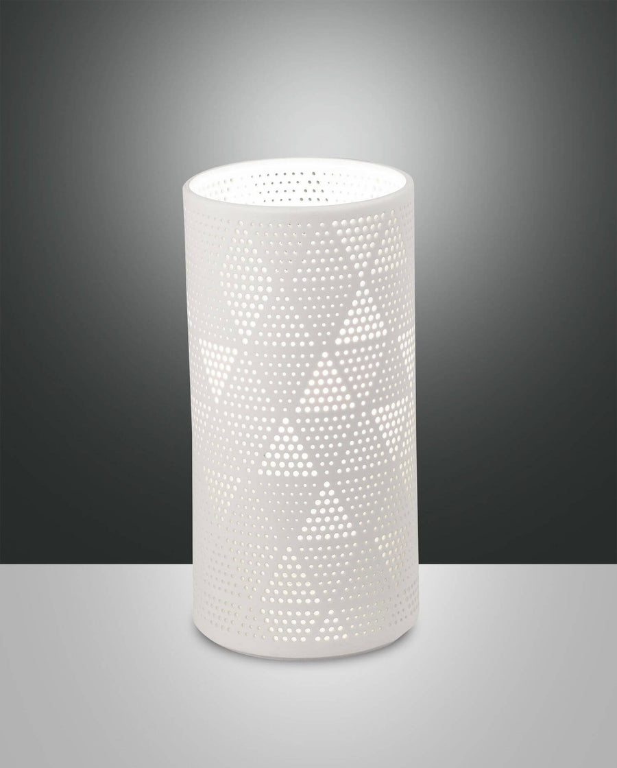 Lampe à poser cylindrique blanche perforée, vue de face sur fond dégradé gris