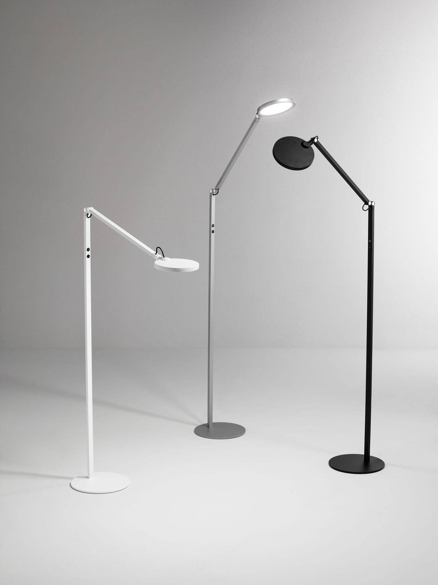Trois lampes sur pied identiques en blanc, gris et noir, présentées côte à côte