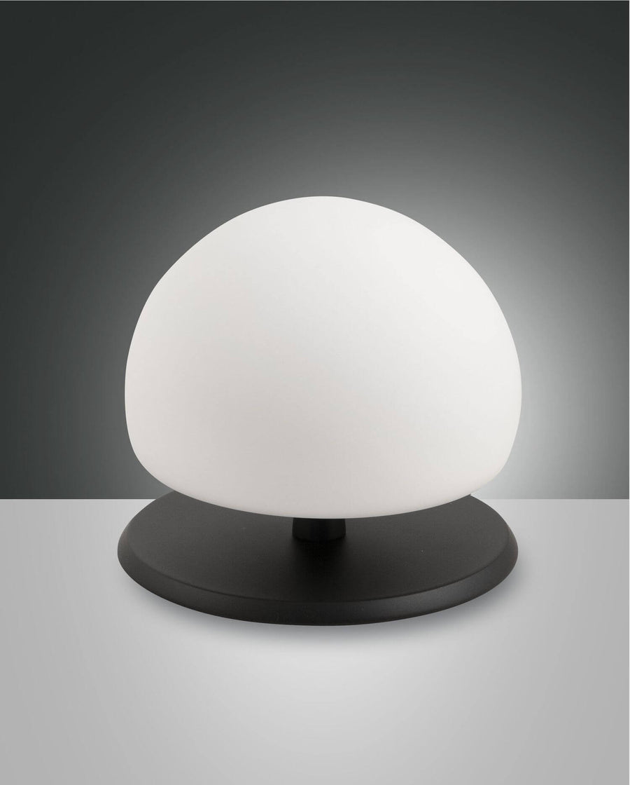 Lampe à poser noire avec diffuseur sphérique blanc, vue de face sur fond gris.