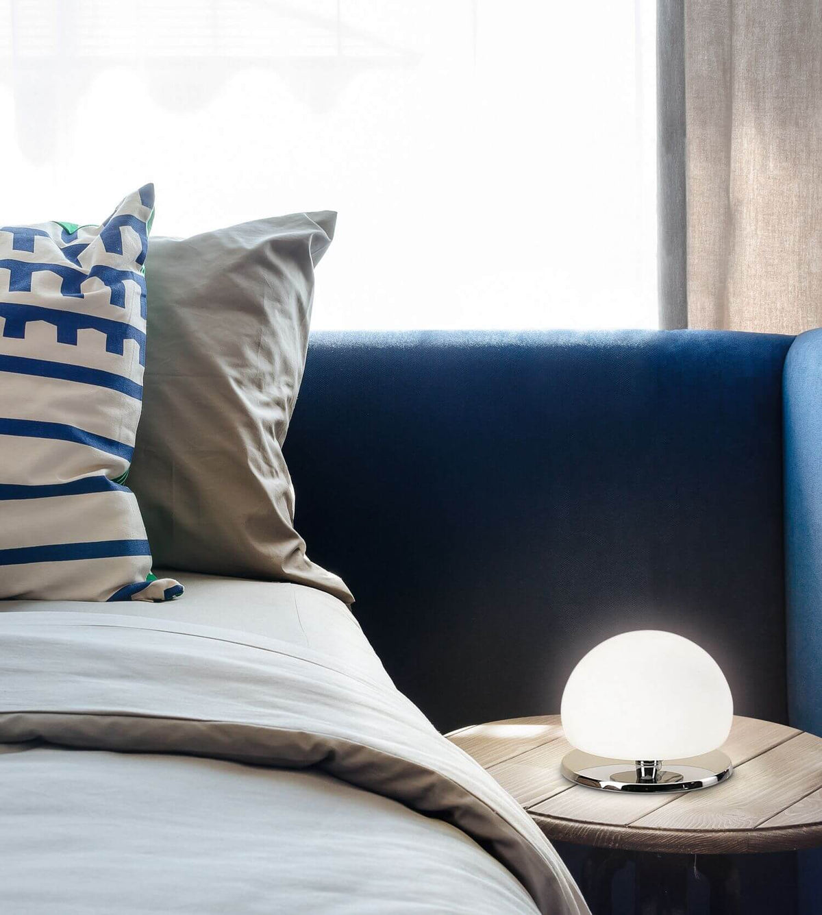 Mise en ambiance sur table de chevet en bois, près d'un lit bleu nuit