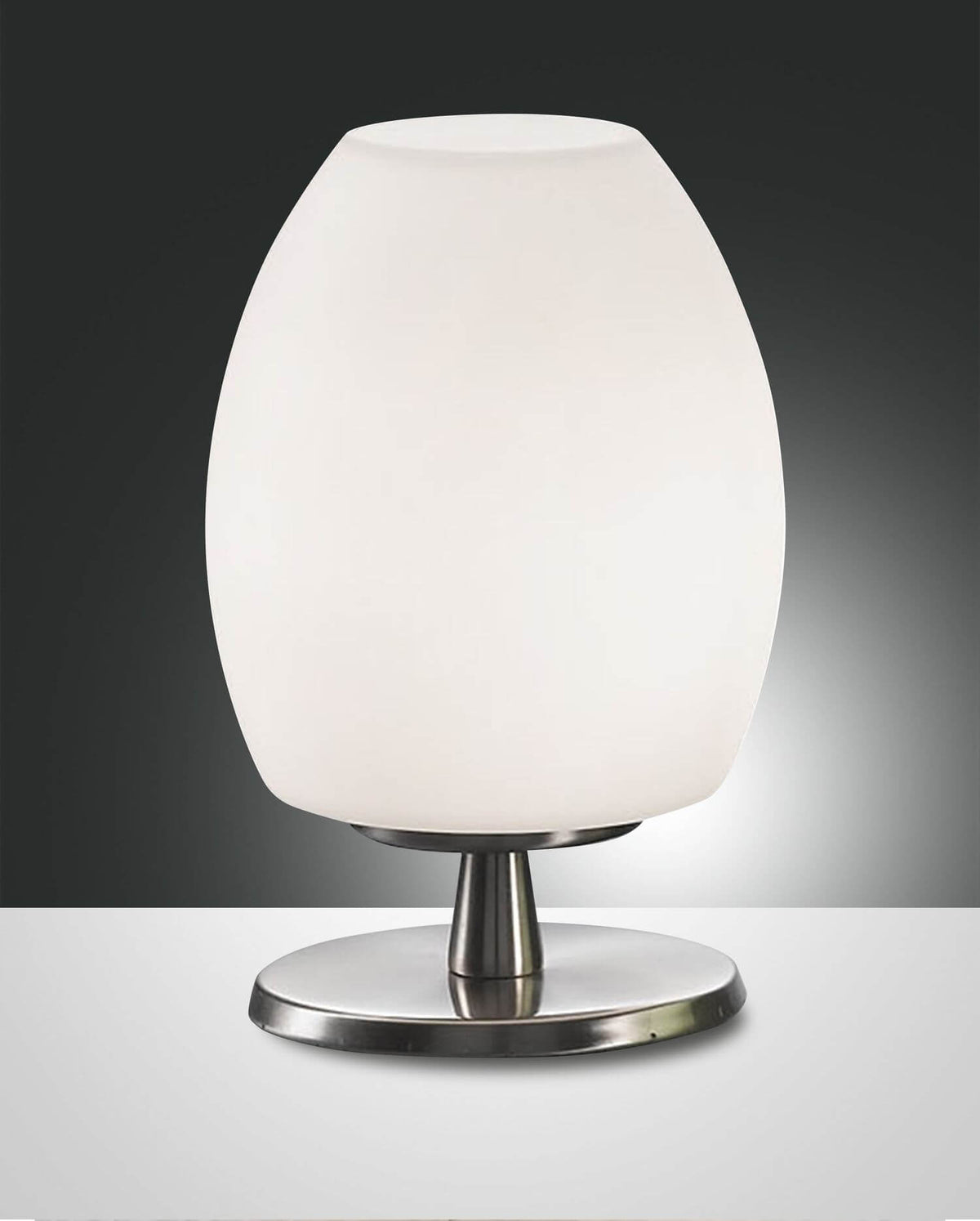 Lampe à poser blanche ovale sur fond gris, vue de face avec base métallique.