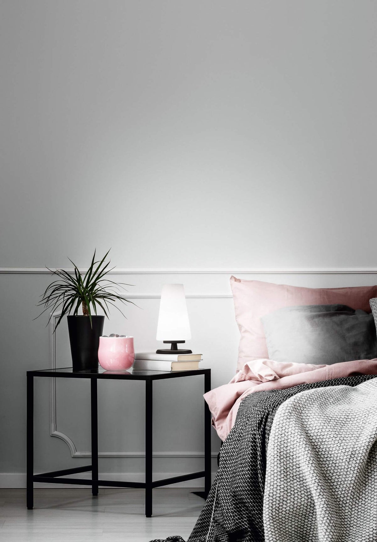 Mise en ambiance : lampe allumée sur table de nuit noire près d'un lit