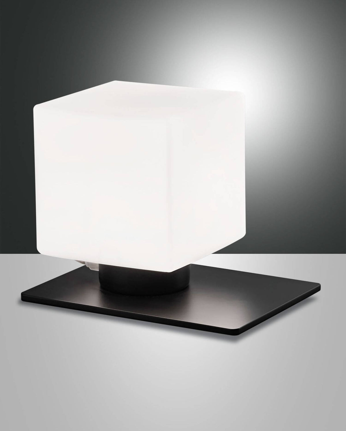 Lampe à poser noire, diffuseur cubique blanc allumé, vue de trois quarts sur fond gris