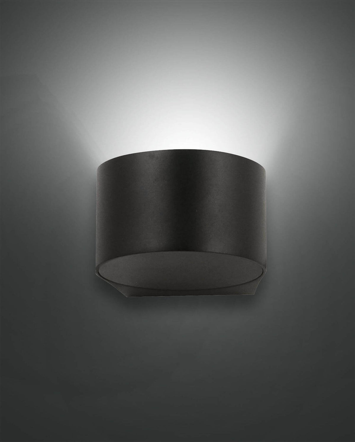 Applique murale noire cylindrique allumée, halo lumineux diffusé vers le haut sur fond gris
