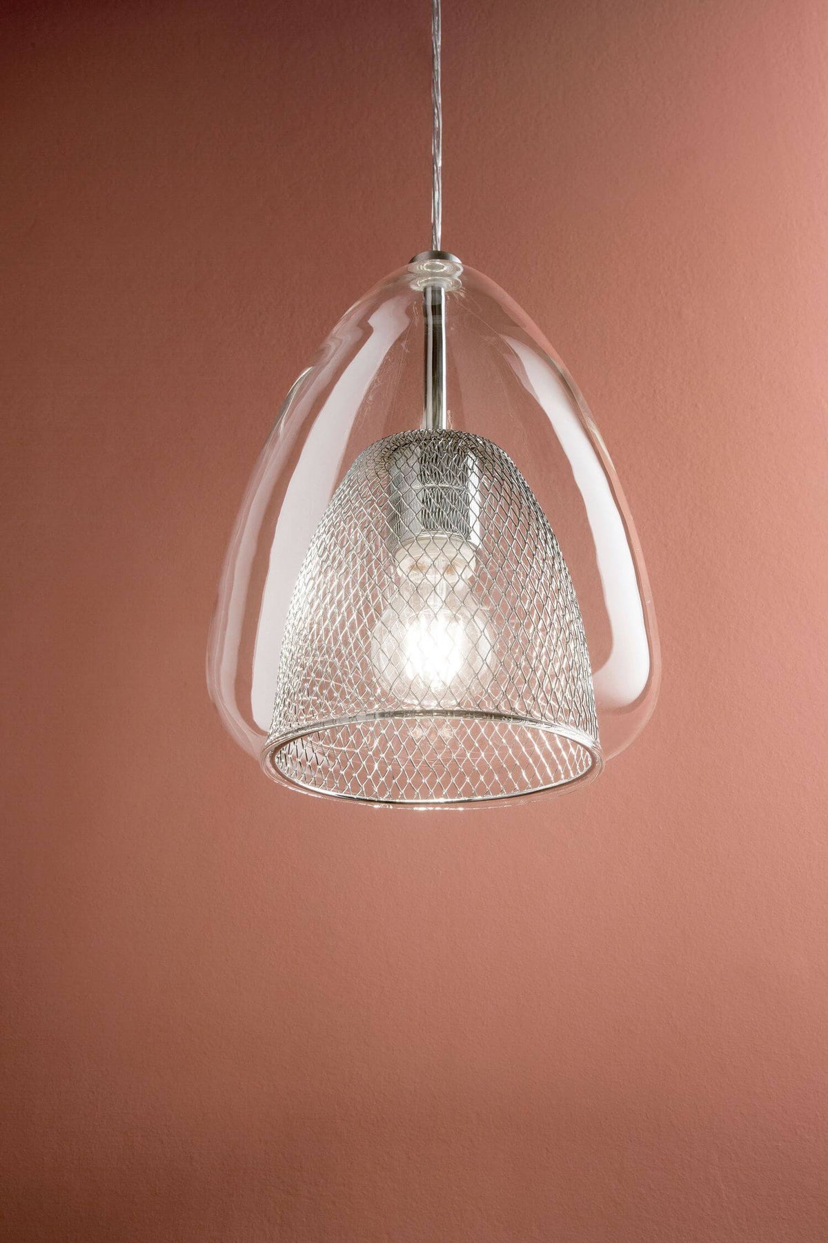 Gros plan sur la suspension transparente et sa grille métallique, fond terracotta