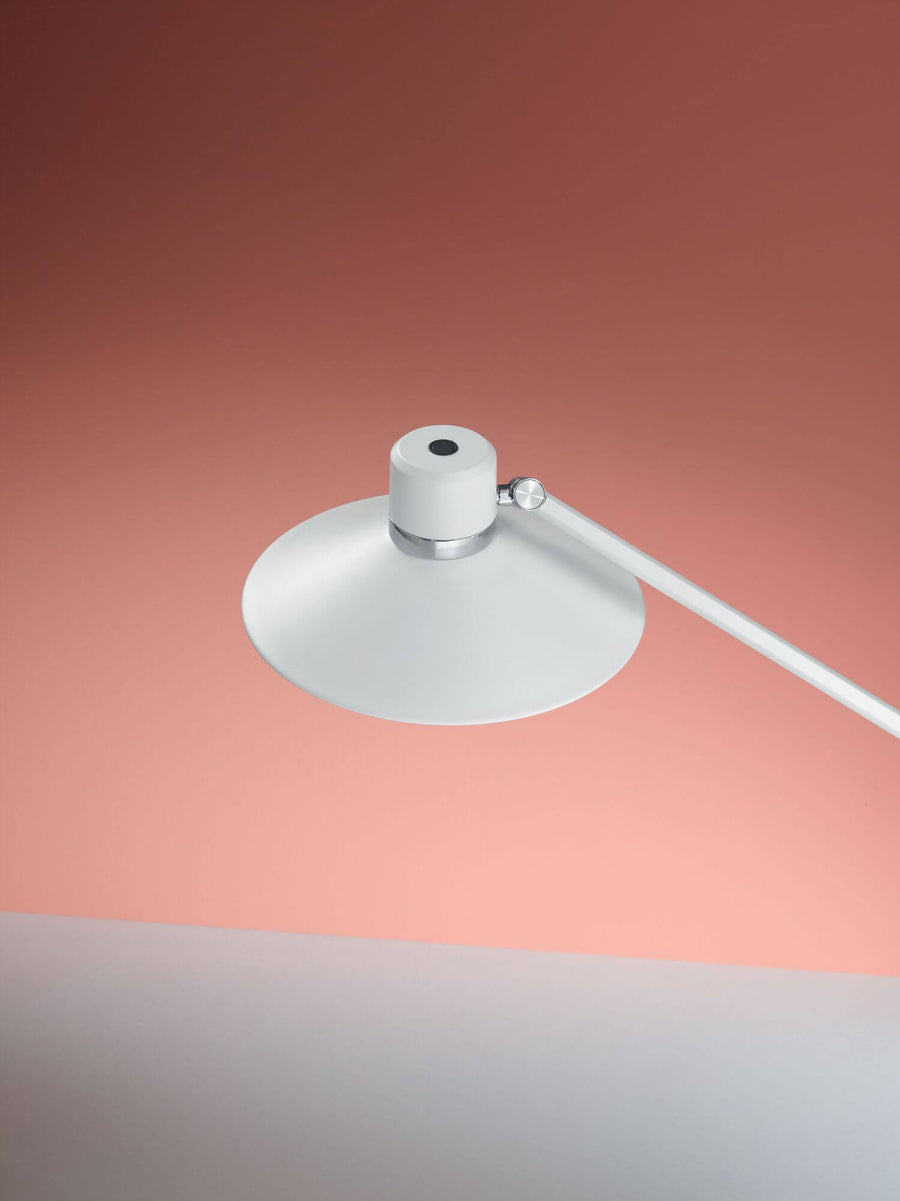 Détail de l'abat-jour conique blanc et de l'articulation chromée, fond rose
