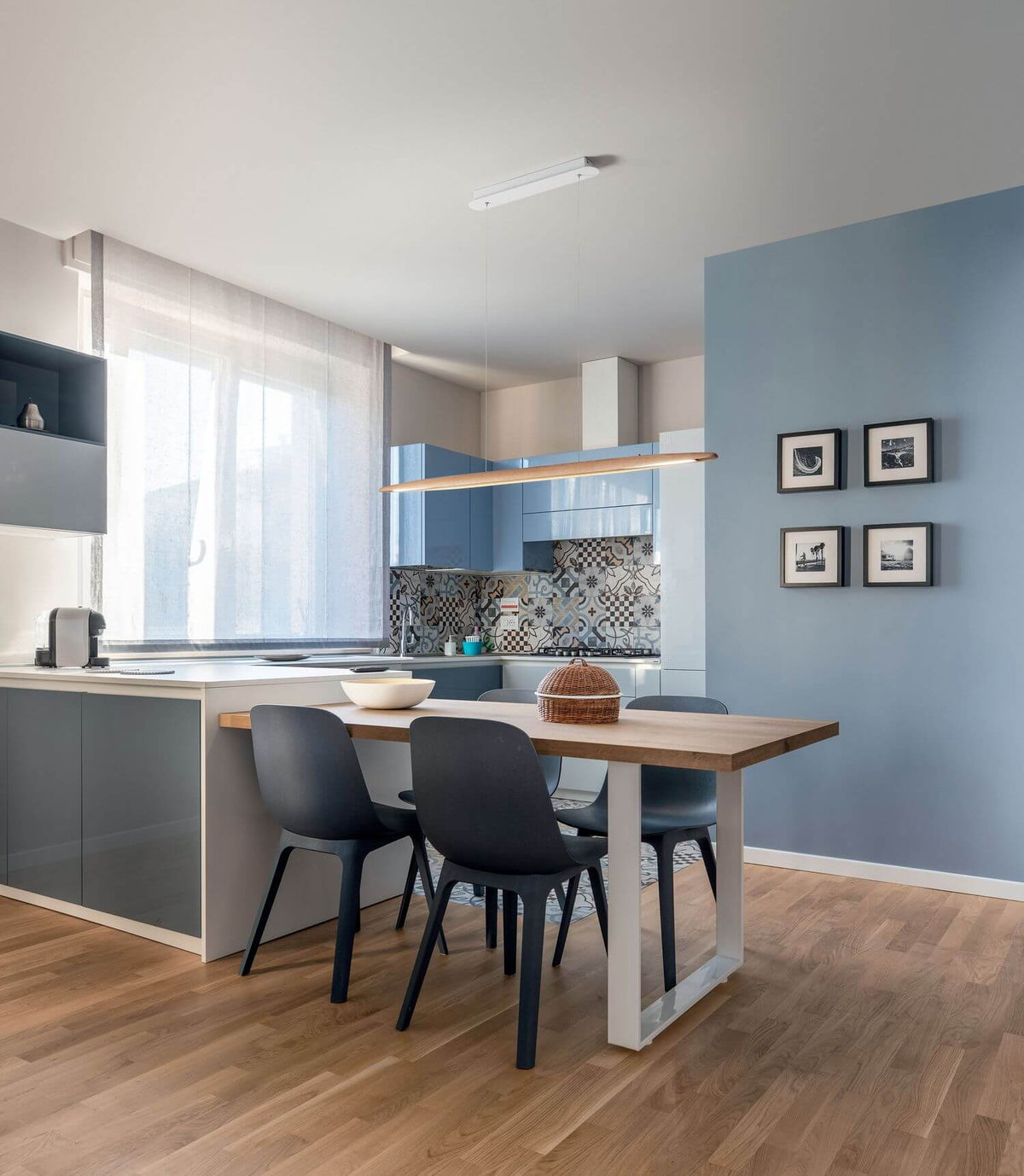 Mise en ambiance : le luminaire éclaire une table de cuisine dans un intérieur bleu