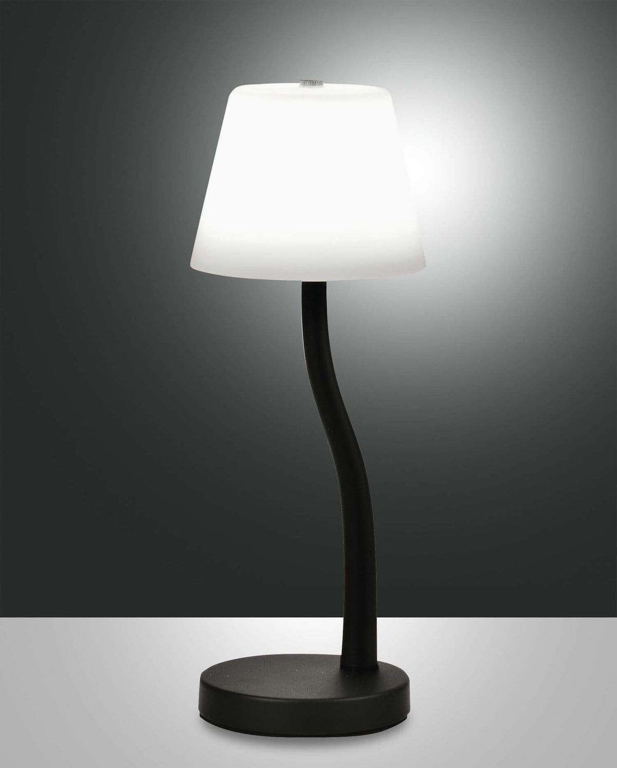 Lampe à poser noire allumée, abat-jour conique blanc et pied incurvé sur fond sombre.