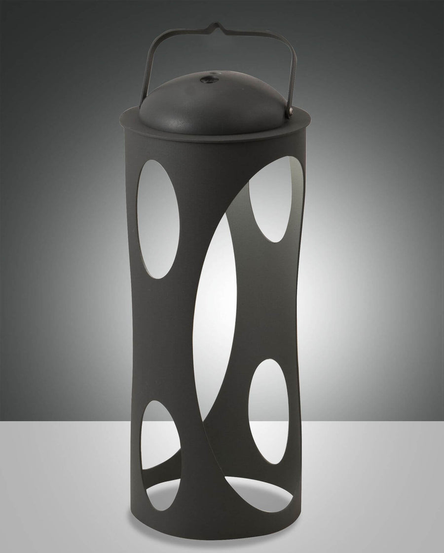 Lanterne cylindrique noire à découpes ovales posée, éclairée de l'intérieur