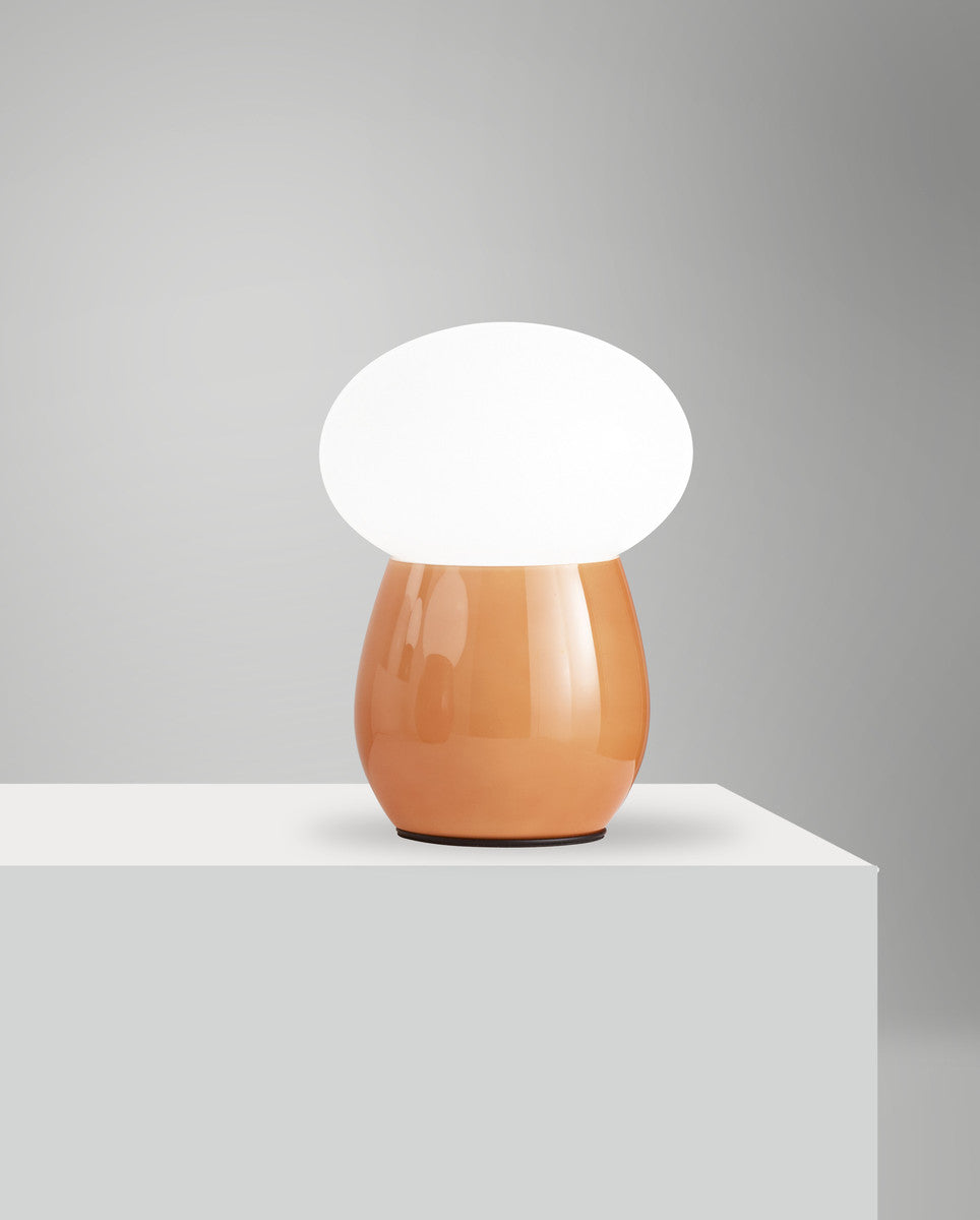 Lampe ambrée éteinte posée sur un cube blanc, mise en ambiance épurée