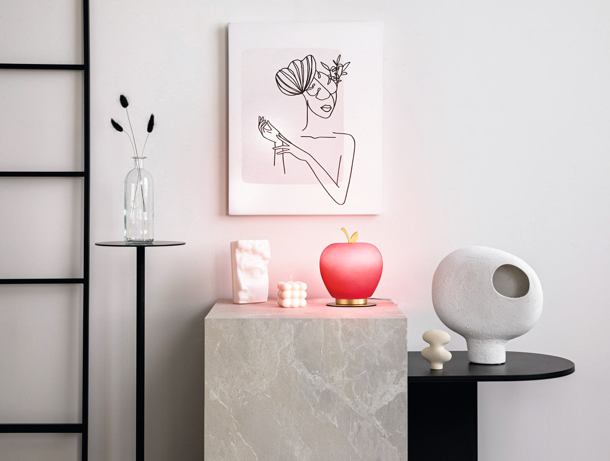 Mise en ambiance sur console en marbre, lampe pomme allumée parmi des objets décoratifs