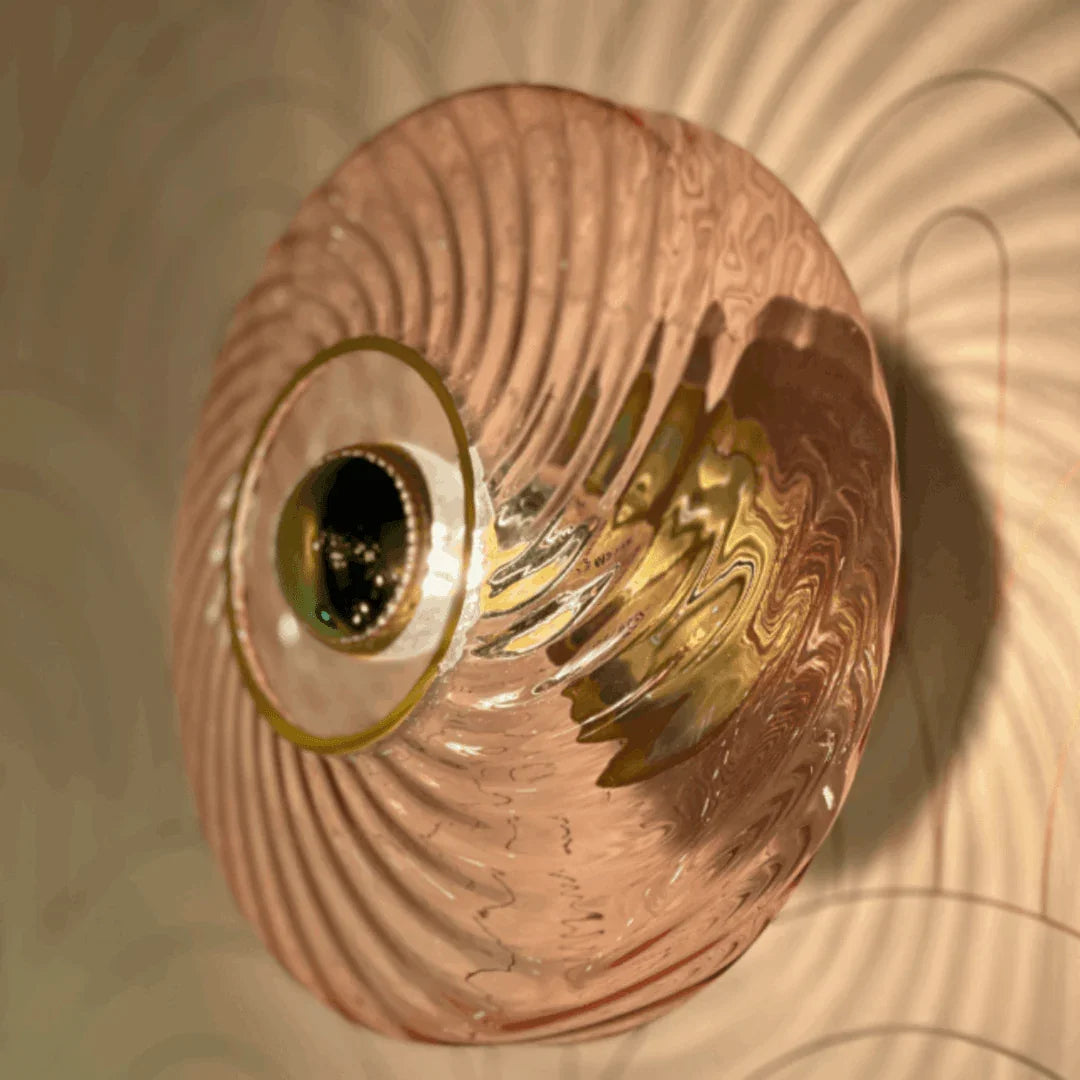 Applique ronde en verre rose strié fixée au mur, éclairage chaud et reflets