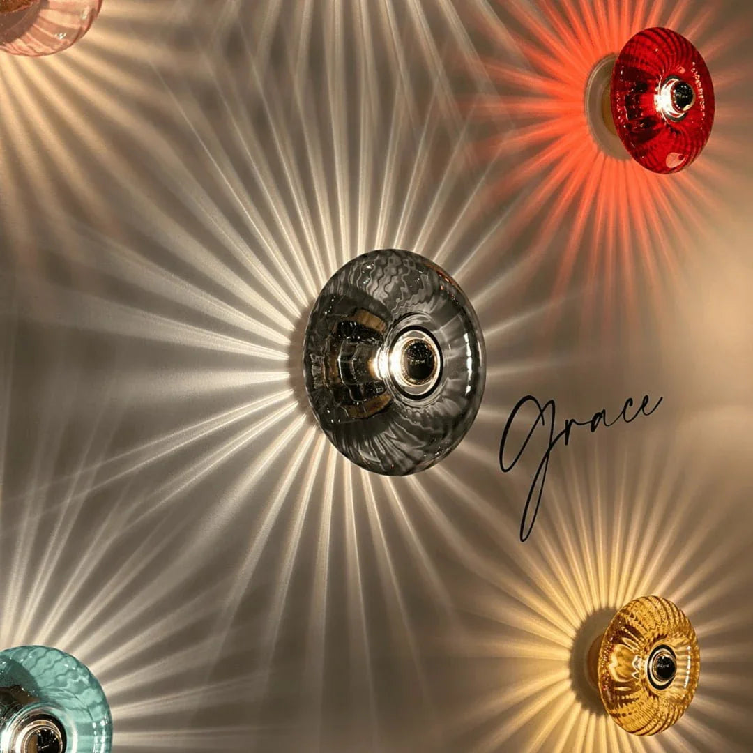 Plusieurs appliques colorées rouge, grise, ambre et turquoise aux halos rayonnants