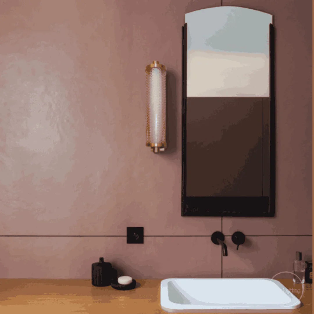 Applique dorée allumée au-dessus d'un plan vasque, reflet dans un miroir rectangulaire