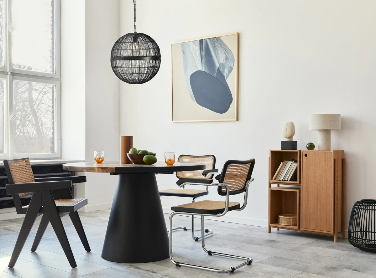 Mise en ambiance dans une salle à manger : suspension noire au-dessus d'une table ronde.