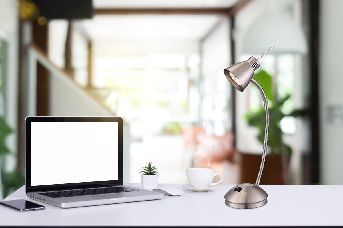 Mise en ambiance sur un bureau avec ordinateur portable, tasse de café et plante verte.