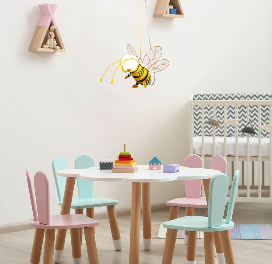 Suspension abeille installée dans une chambre d'enfant au-dessus d'une table pastel.