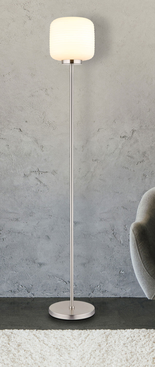 Mise en ambiance du lampadaire dans un intérieur gris, près d'un fauteuil.