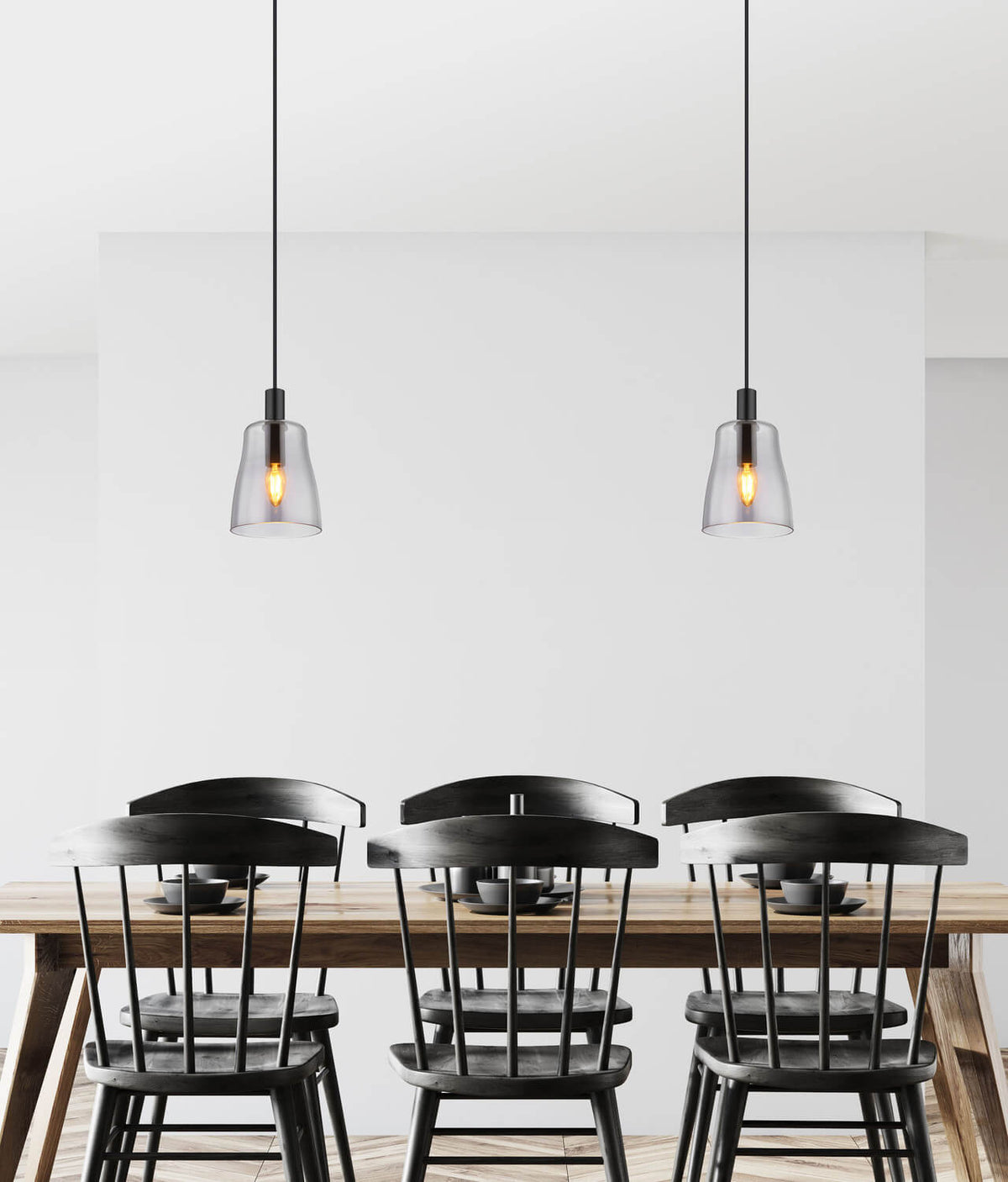Mise en ambiance avec deux suspensions noires au-dessus d'une table en bois et chaises noires.
