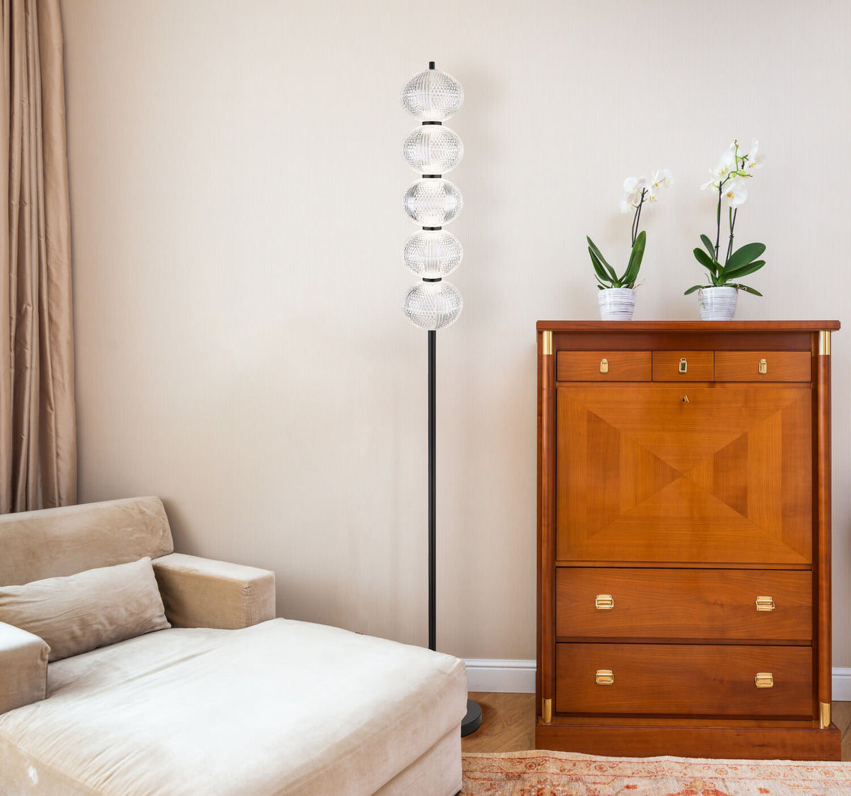 Mise en ambiance salon : lampadaire allumé près d'un canapé beige et d'une commode bois
