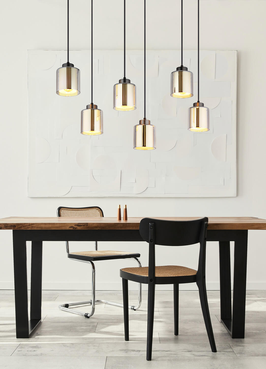 Mise en ambiance au-dessus d'une table à manger en bois, avec chaises noires et cannage