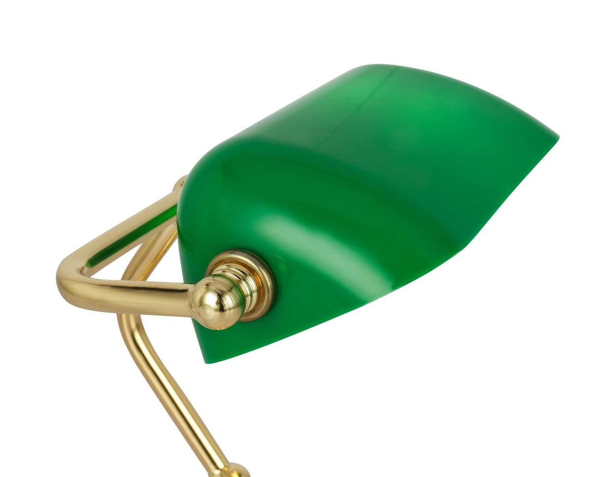 Gros plan sur l'abat-jour vert et l'articulation en laiton doré de la lampe.