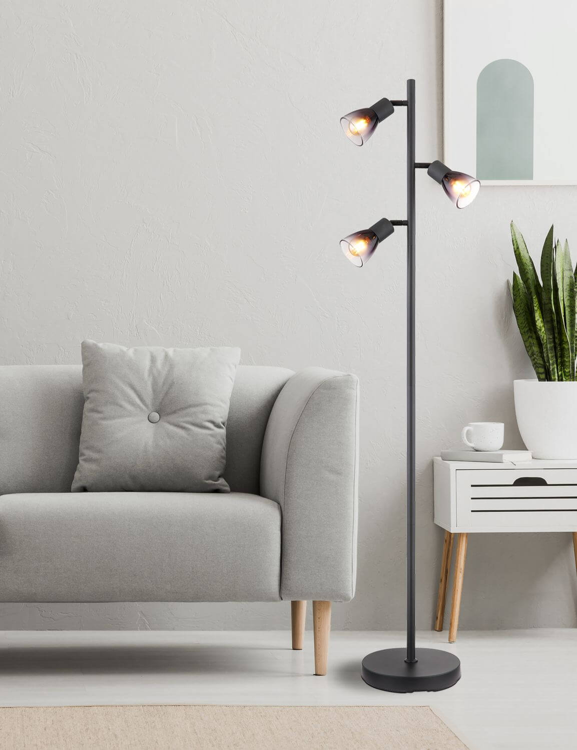 Mise en ambiance du lampadaire allumé près d'un fauteuil gris et d'une commode blanche