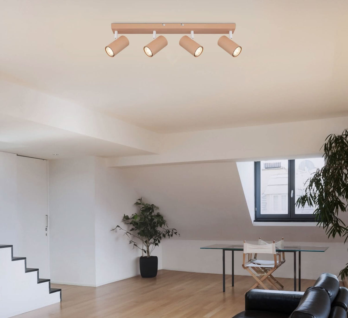 Spot quatre projecteurs beige installé au plafond dans un salon blanc, éclairant la pièce.