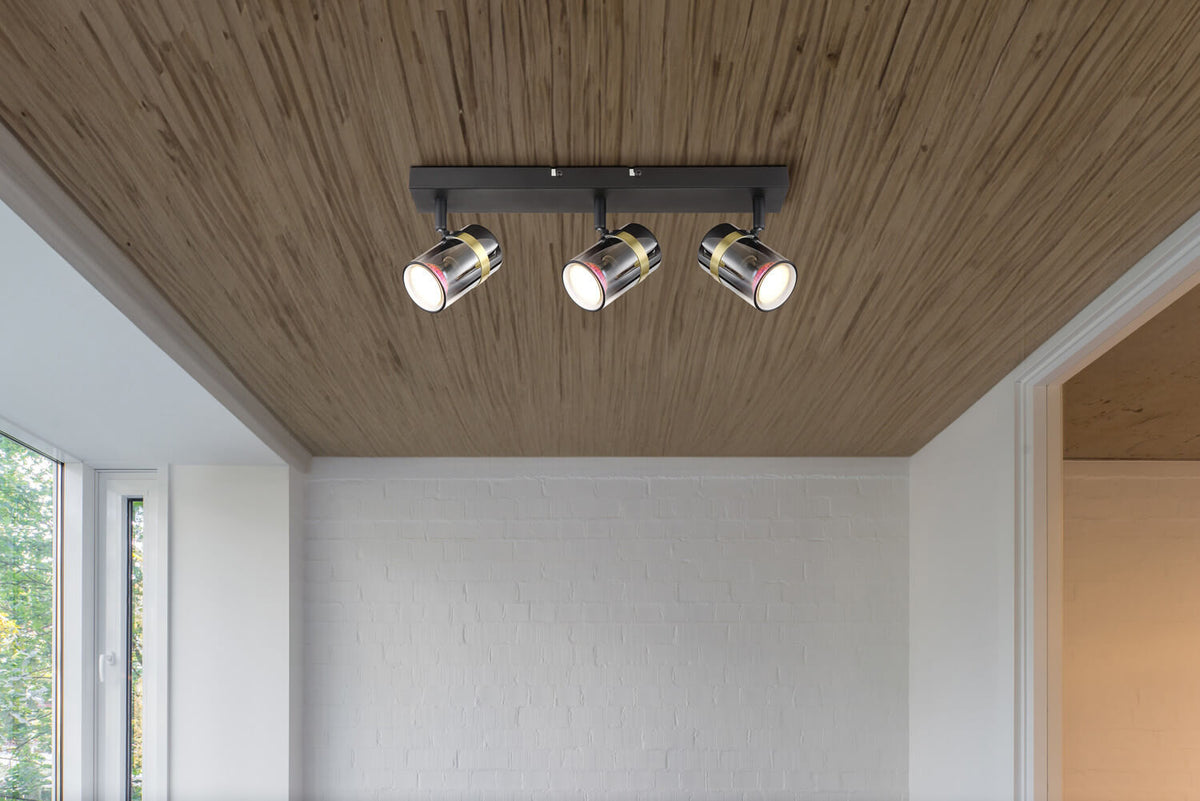 Spot installé au plafond dans une pièce avec plafond en bois et mur blanc.
