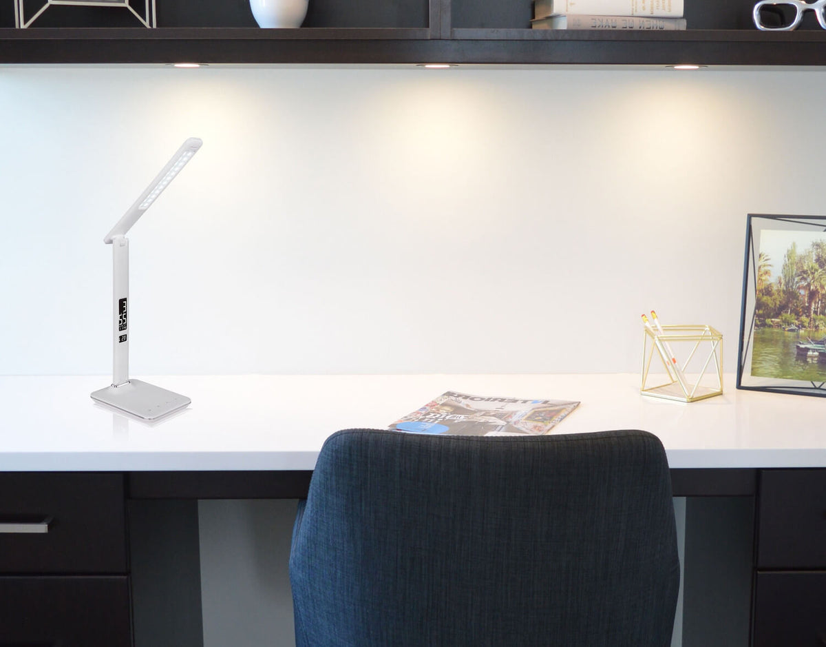 Lampe blanche posée sur un bureau blanc dans un intérieur contemporain avec chaise et étagères.