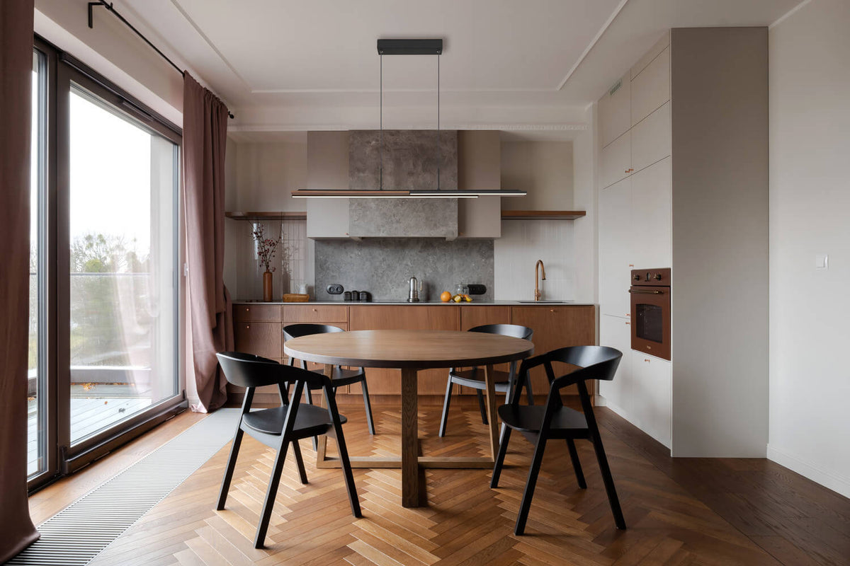 Mise en ambiance au-dessus d'une table ronde dans une cuisine bois et béton clair.