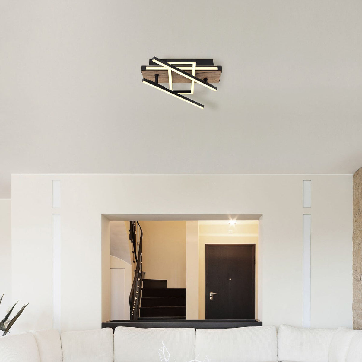 Plafonnier installé au plafond dans une pièce blanche avec ouverture sur un escalier.