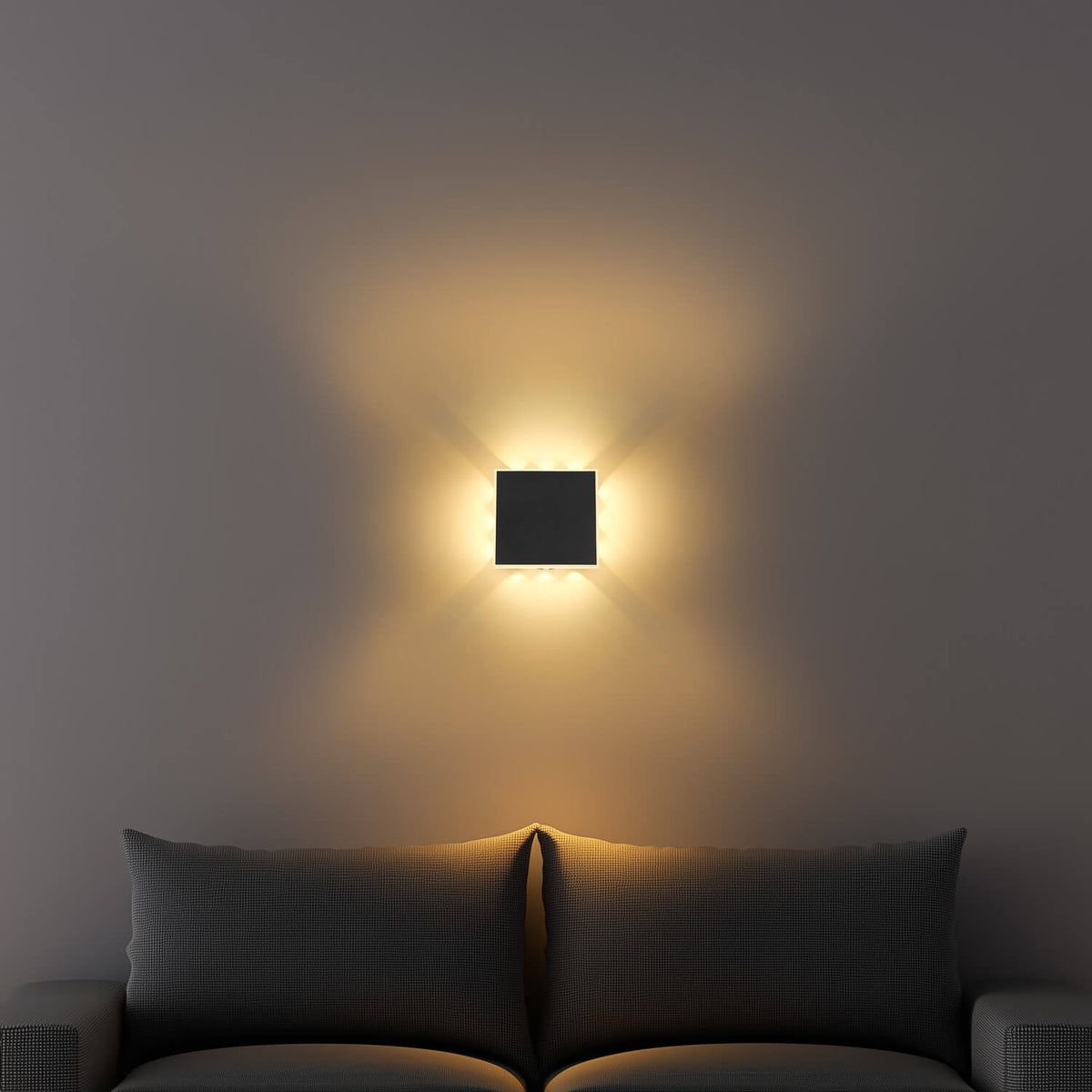Mise en ambiance : applique allumée diffusant une lumière chaude sur mur derrière un canapé